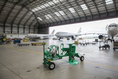 Green oxygen ground support equipment cart inside an aircraft maintenance hangar with commercial jets.