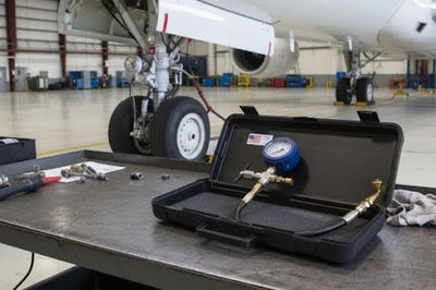 Aircraft tire pressure gauge ground support tool in a case with an ATR landing gear in the background.