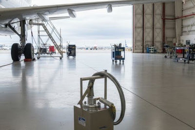Hydraulic ground support equipment unit positioned inside an aircraft hangar with service carts nearby.